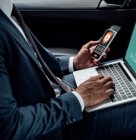 cropped view of african american businessman using laptop and smartphone in car with cyber security